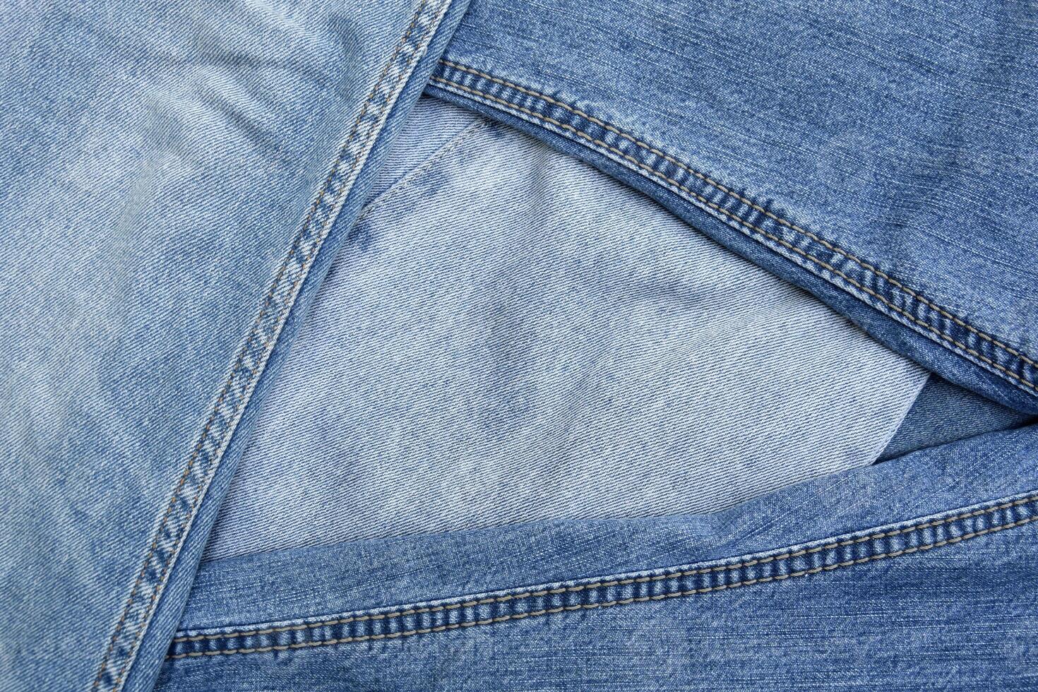 Lots of jeans pants in a stack. Denim background. photo