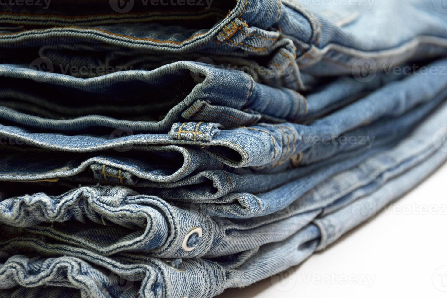 Lots of jeans pants in a stack. Denim background. photo