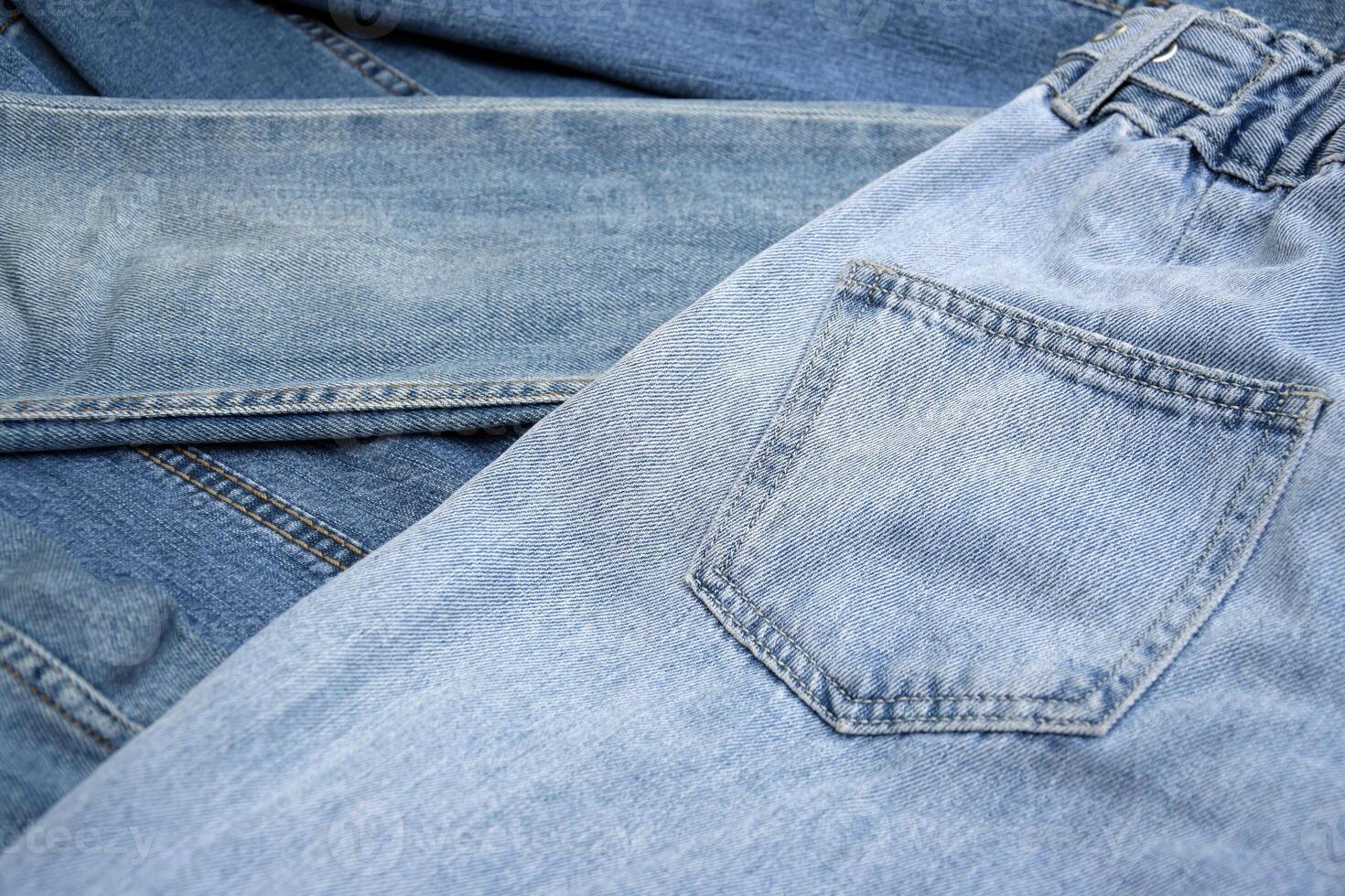 Lots of jeans pants in a stack. Denim background. photo