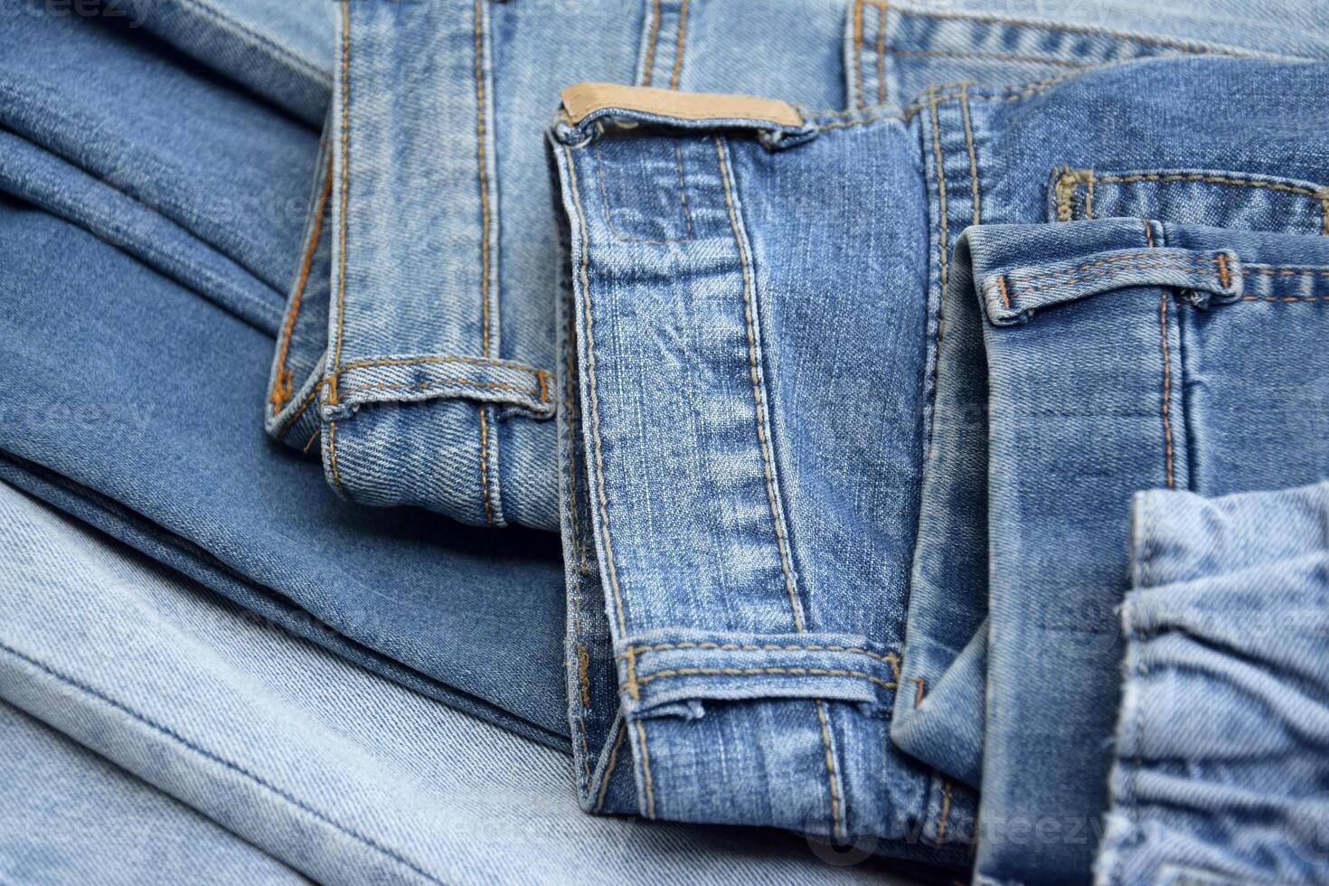 Lots of jeans pants in a stack. Denim background. photo