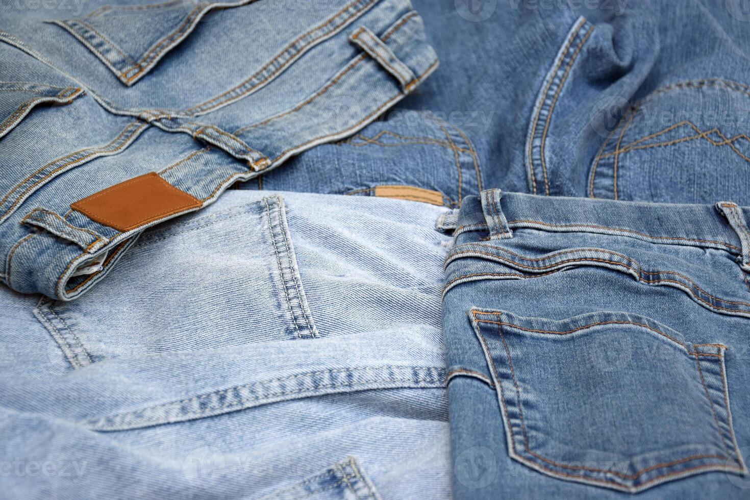 Lots of jeans pants in a stack. Denim background. photo