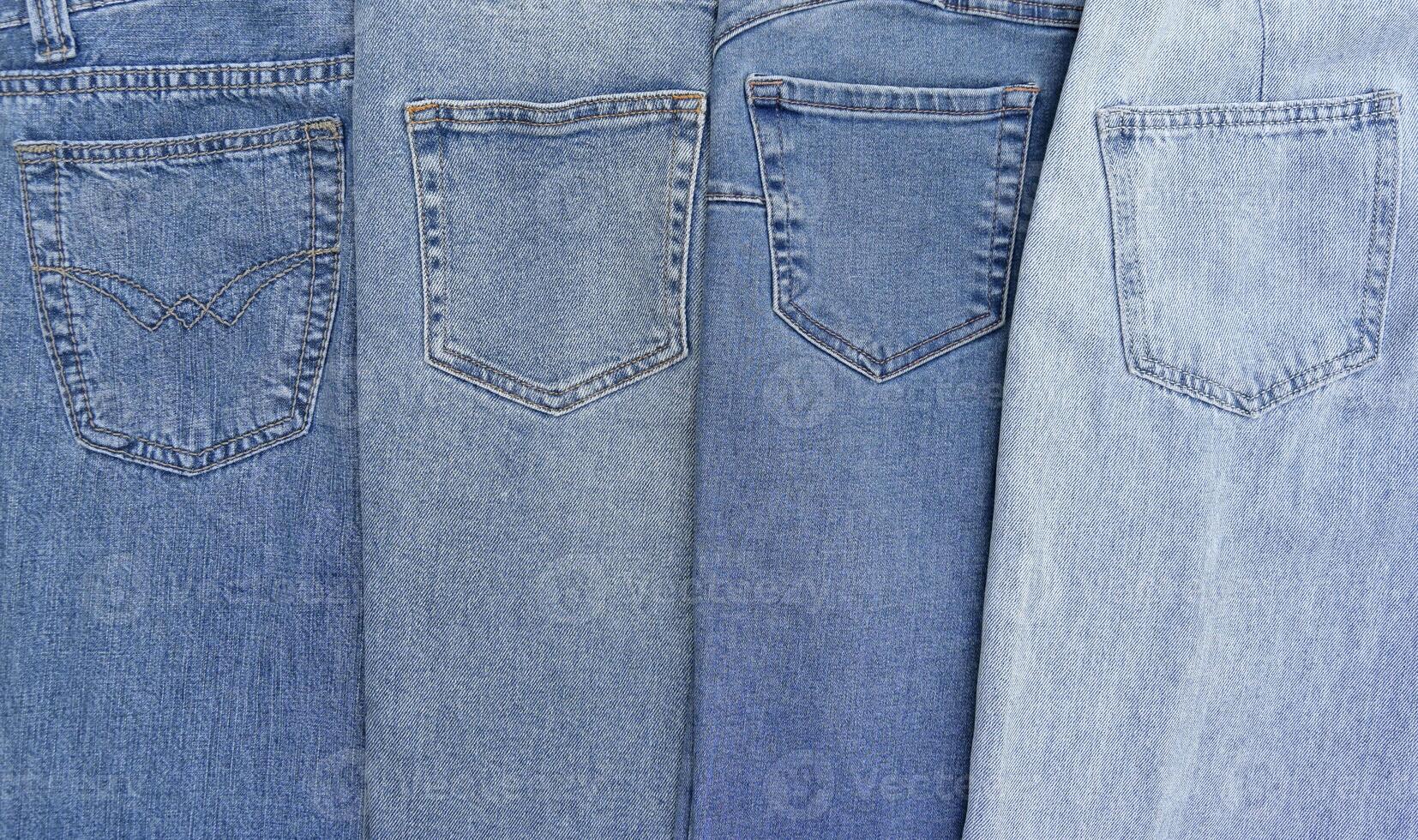 Lots of jeans pants in a stack. Denim background. photo