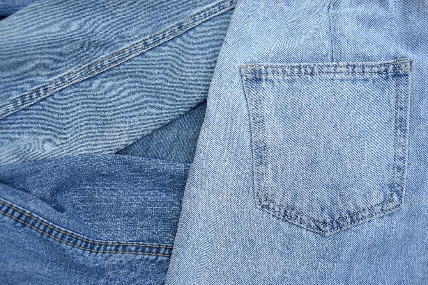 Lots of jeans pants in a stack. Denim background. photo