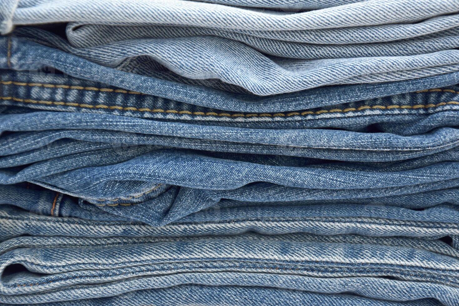 Lots of jeans pants in a stack. Denim background. photo