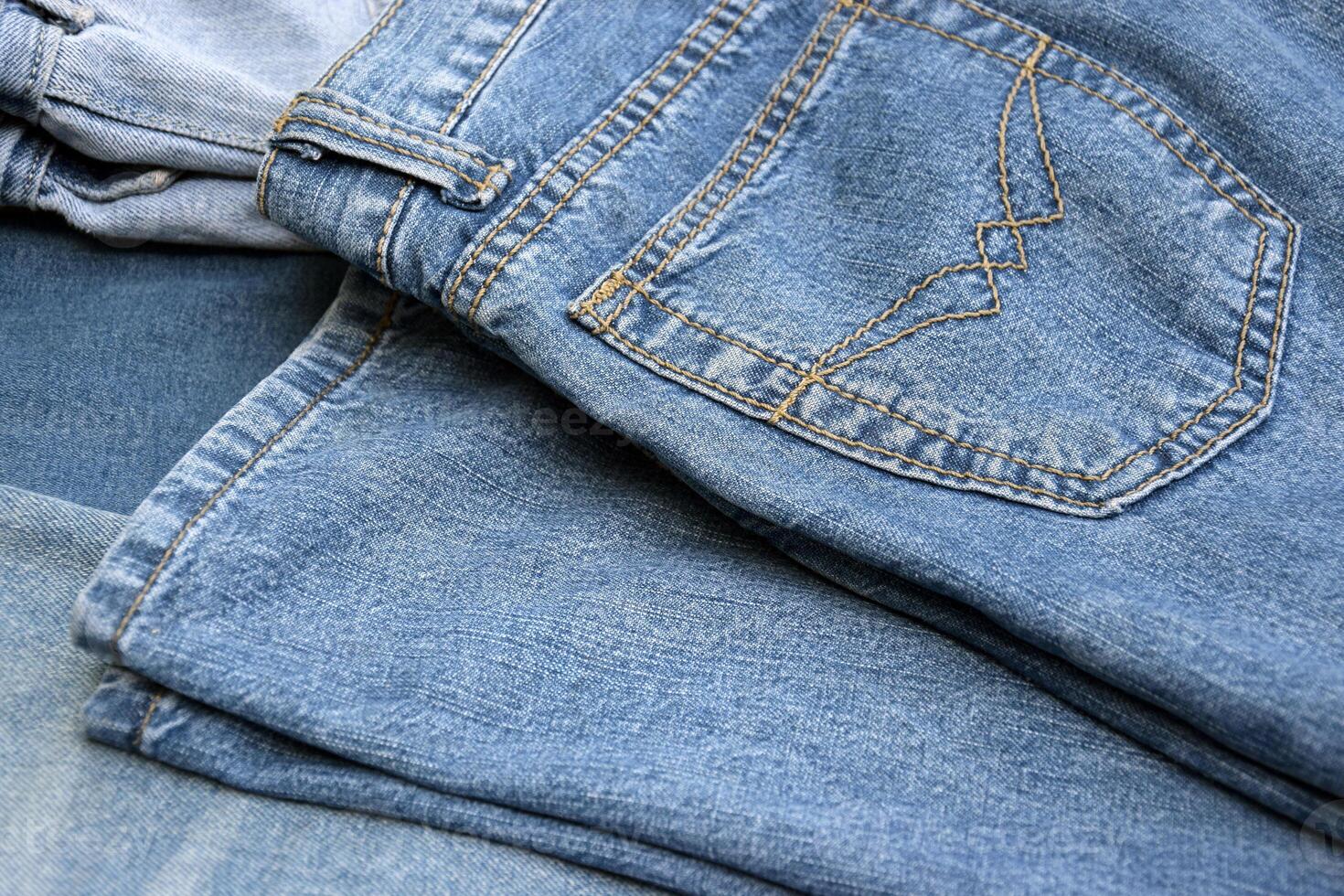 Lots of jeans pants in a stack. Denim background. photo