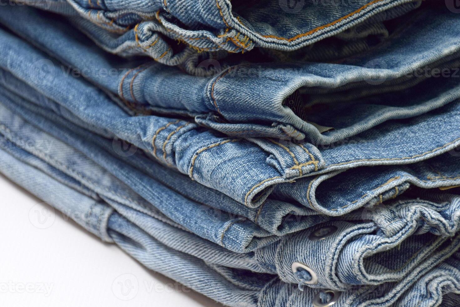 Lots of jeans pants in a stack. Denim background. photo