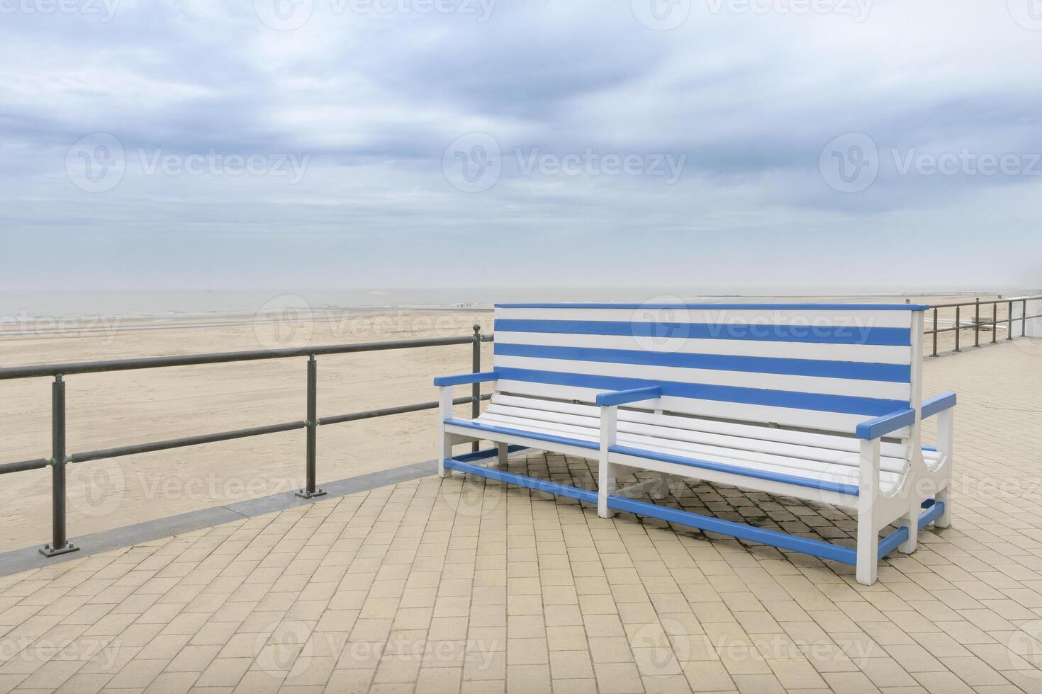 A large beautiful bench on a deserted autumn sea beach at sea. White-blue striped color. Copy space. concept photo