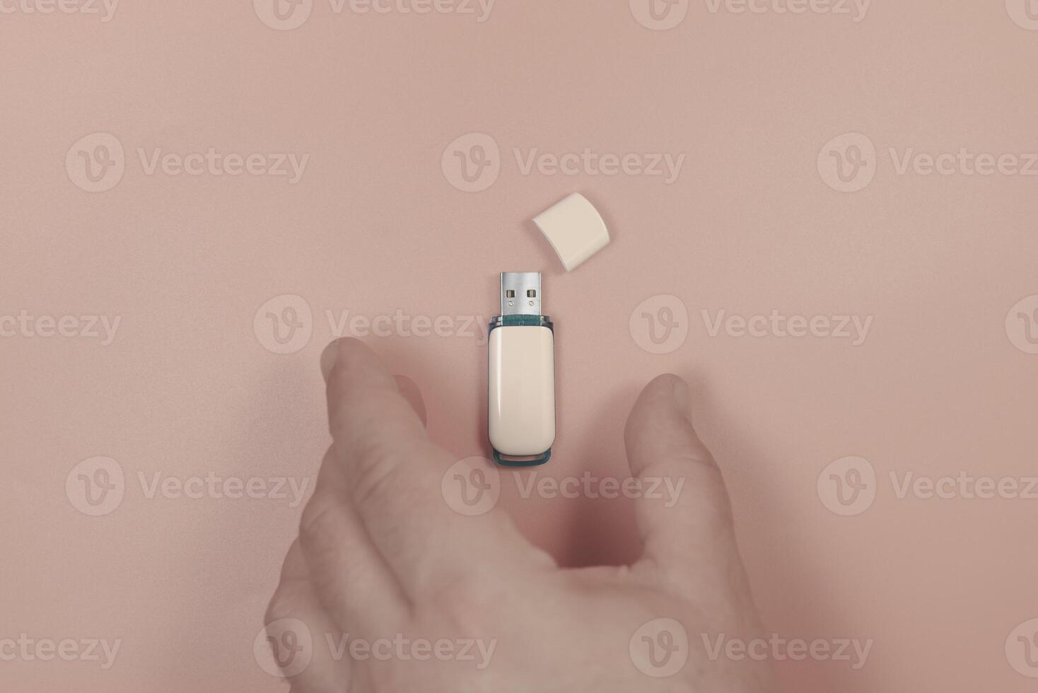 The hand takes a USB stick. On a pink background. Close-up photo