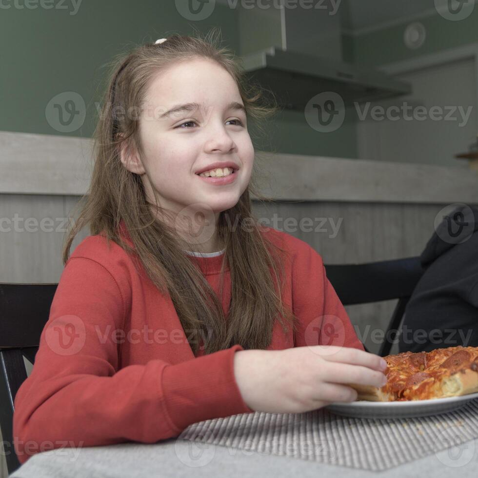 A teenage girl eats pizza. Portrait of a smiling girl at dinner in a red sweater. square format photo