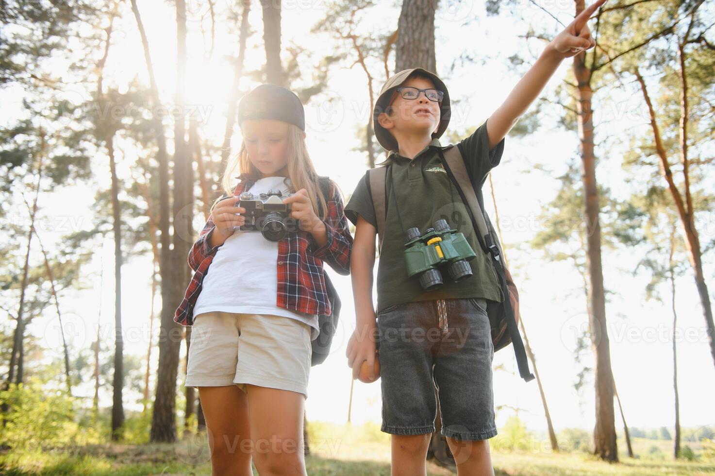boy and girl go hiking with backpacks on forest road bright sunny day photo