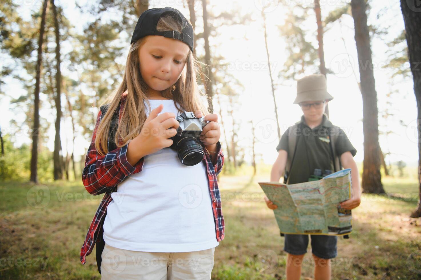 Group of curious happy school kids in casual clothes with backpacks exploring nature and forest together on sunny autumn day. photo