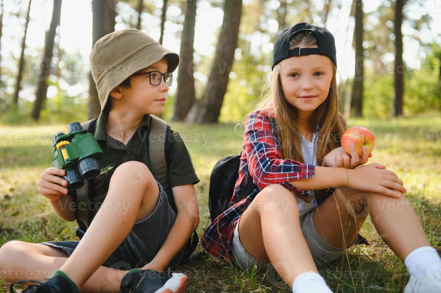 Two happy children having fun during forest hike on beautiful day in pine forest. Cute boy scout with binoculars during hiking in summer forest. Concepts of adventure, scouting and hiking tourism photo