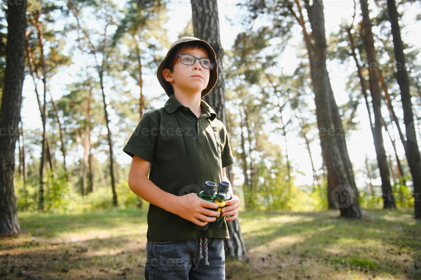Little boy scout with binoculars during hiking in autumn forest. Concepts of adventure, scouting and hiking tourism for kids. photo