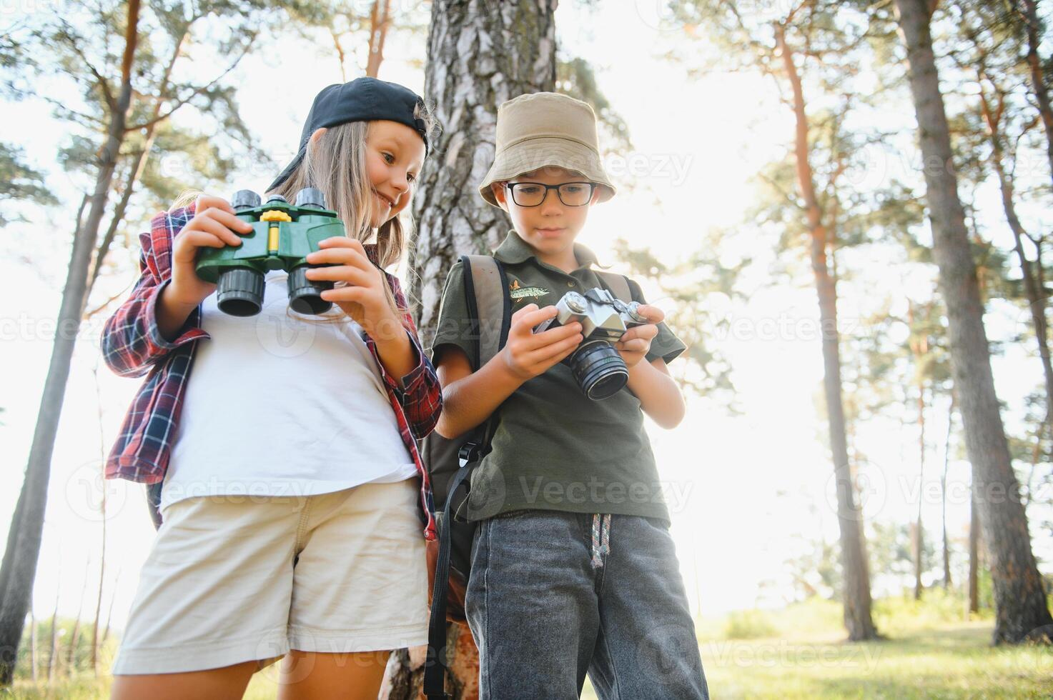 Happy excited school children with backpacks in casual clothes enjoying walk in forest on sunny autumn day, two active kids boy and girl running and playing together during camping trip in nature. photo