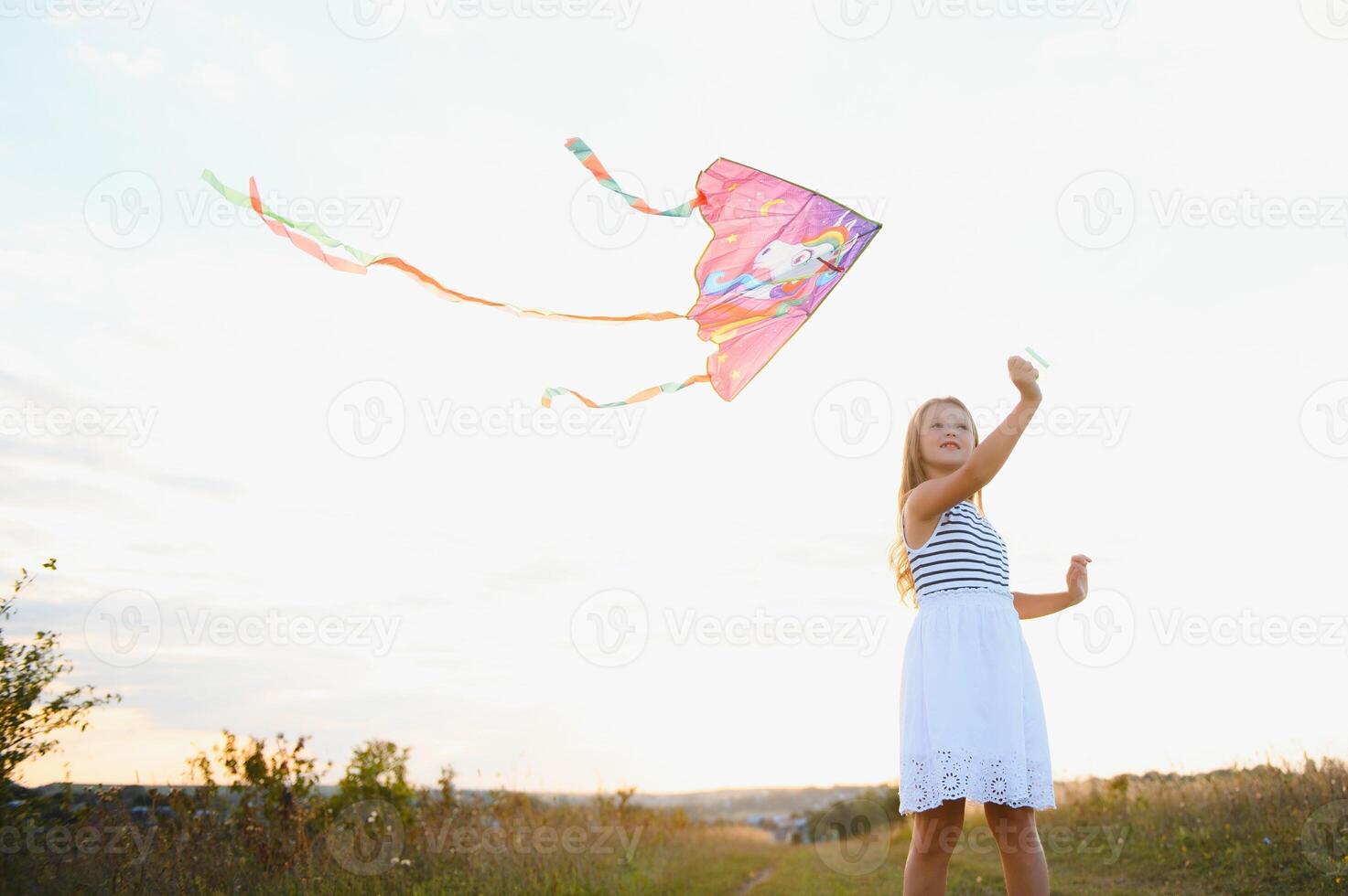 Little cute 7 years old girl running in the field with kite on summer day photo