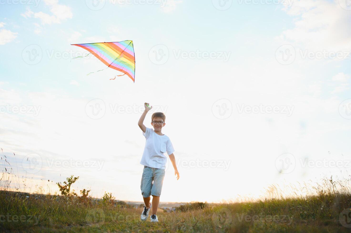 Boy is running with a kite during the day in the field photo