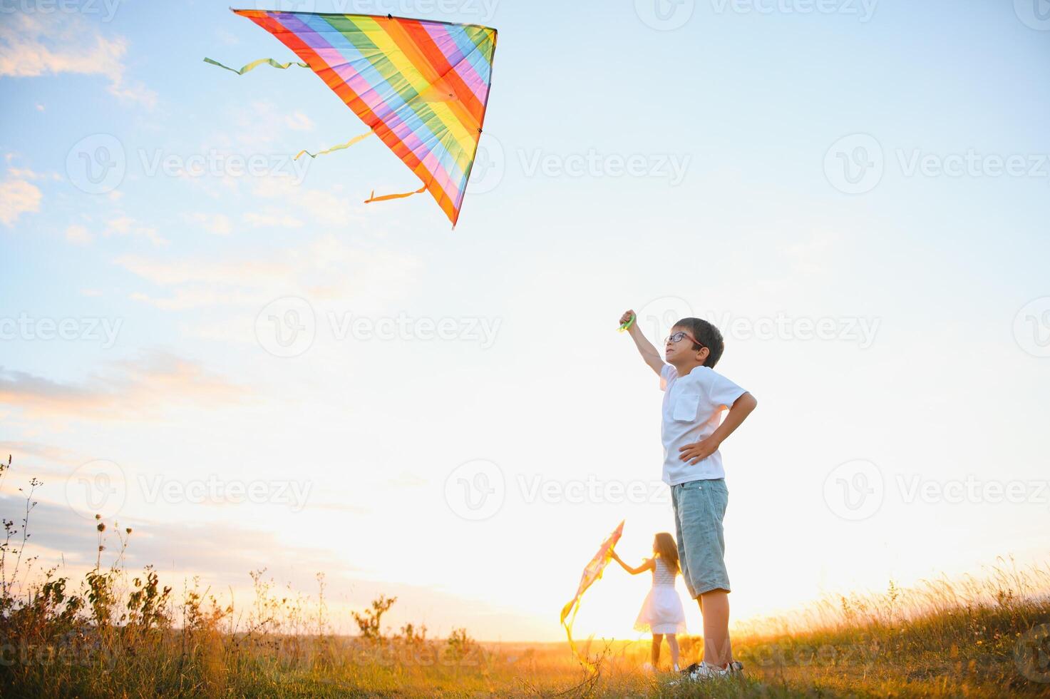Children launch a kite in the field at sunset photo