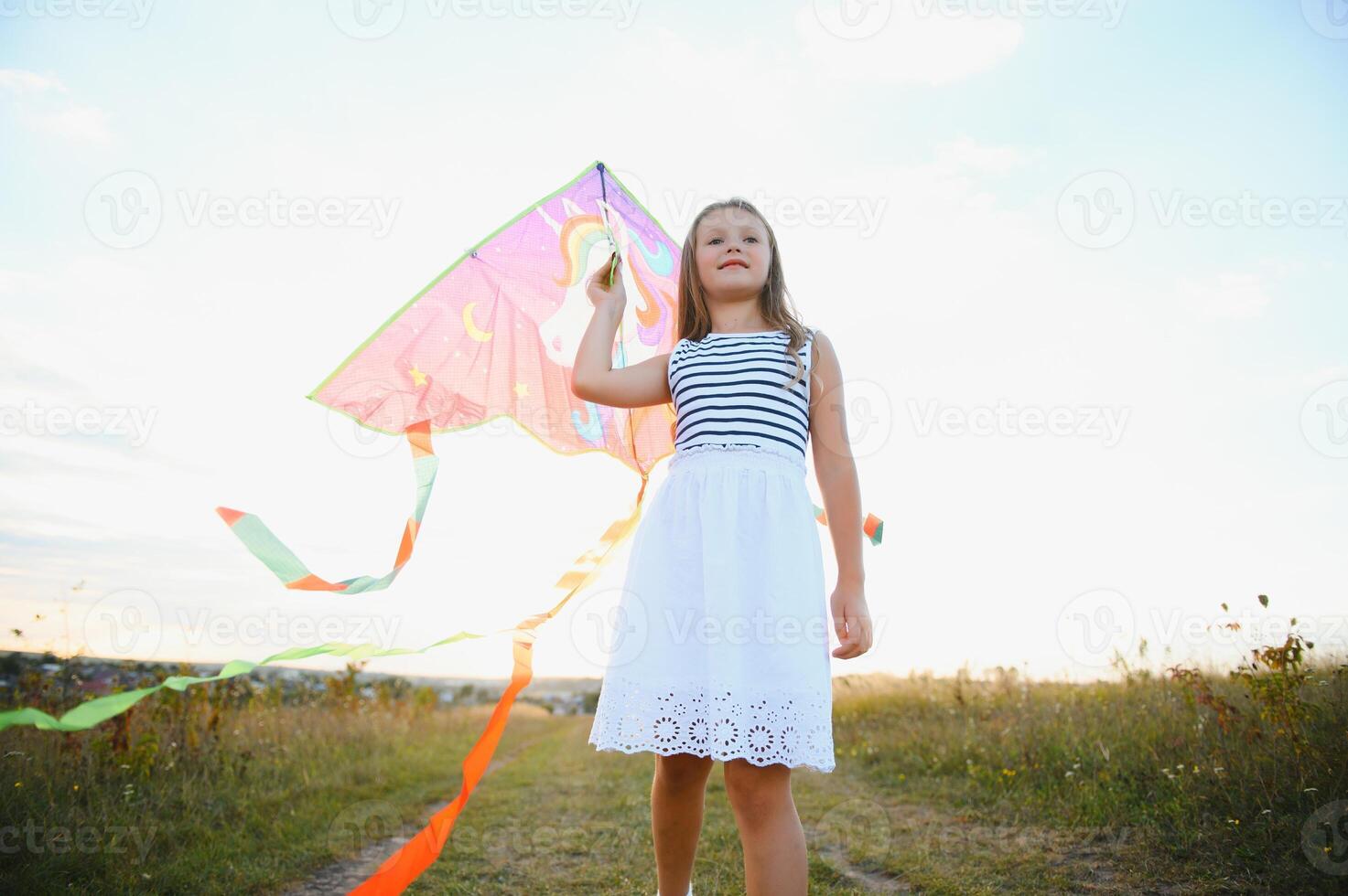 happy child girl with a kite running on meadow in summer in nature photo