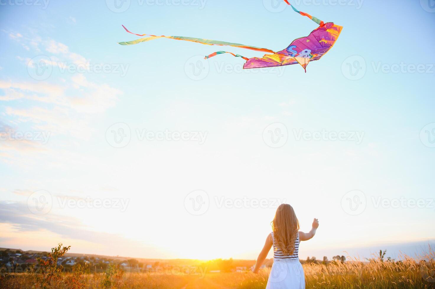 happy child girl with a kite running on meadow in summer in nature photo