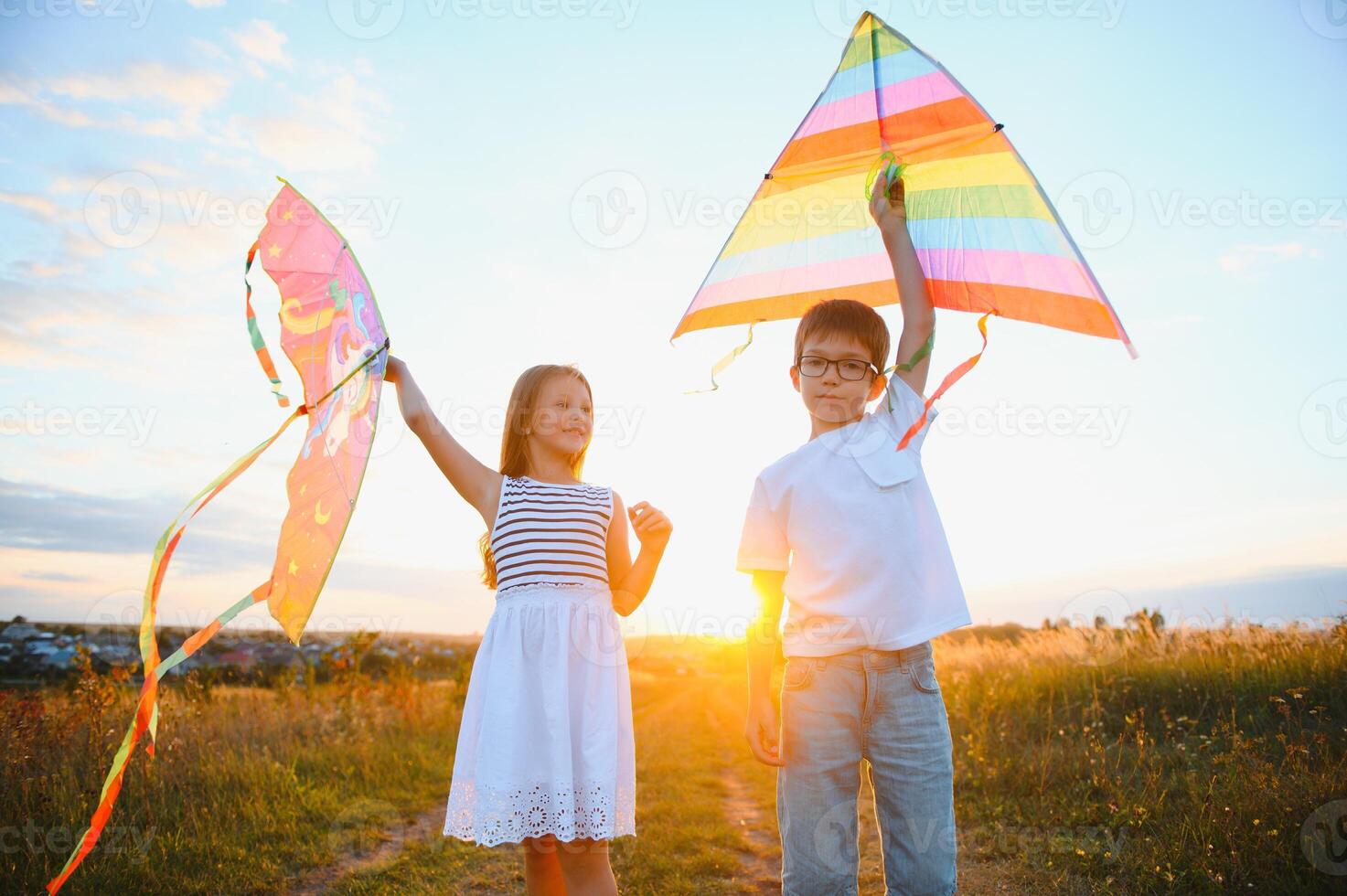 Children launch a kite in the field at sunset photo