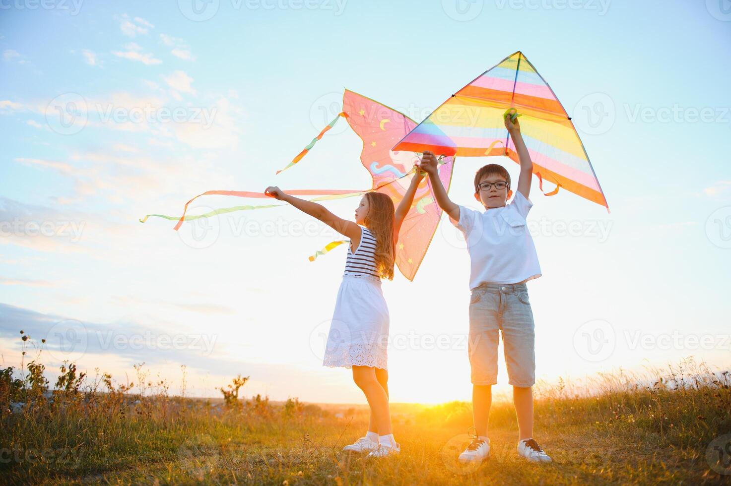 Happy children launch a kite in the field at sunset. Little boy and girl on summer vacation. photo