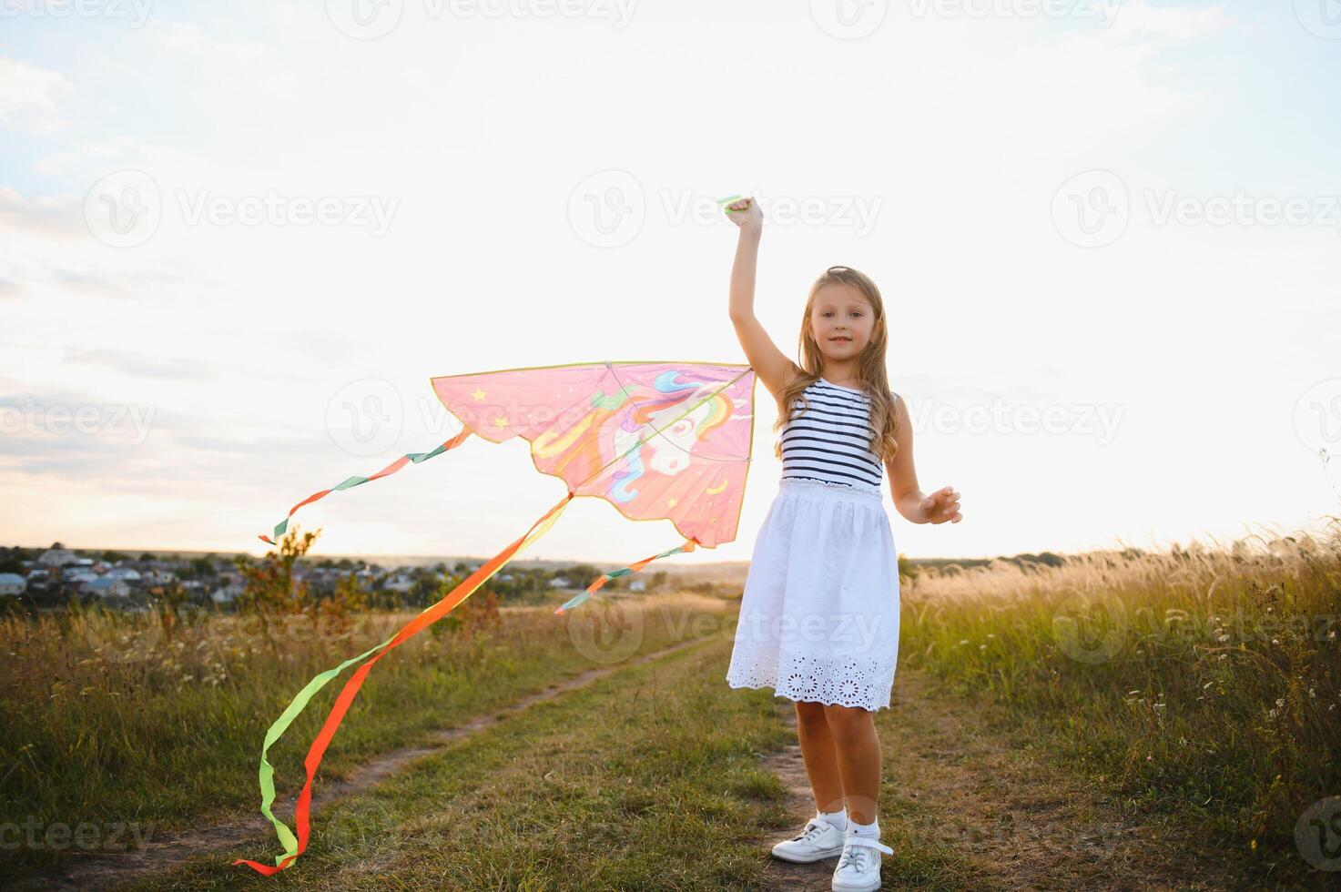 happy child girl with a kite running on meadow in summer in nature photo