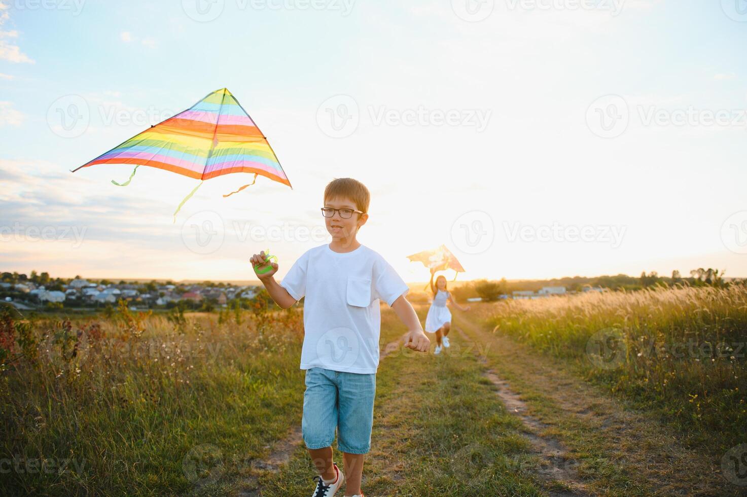 Brother and sister playing with kite and plane at the field on the sunset. photo