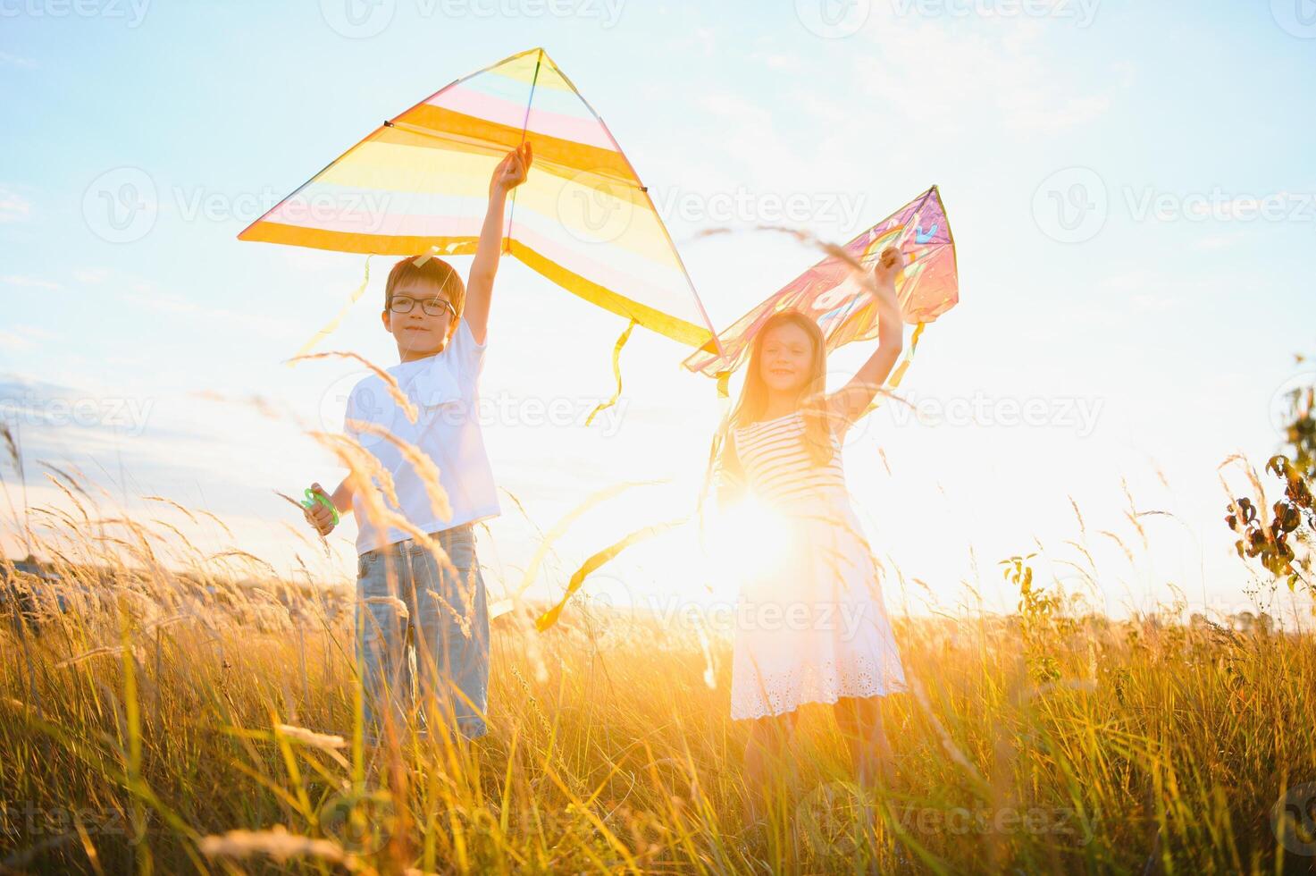 Children launch a kite in the field at sunset photo
