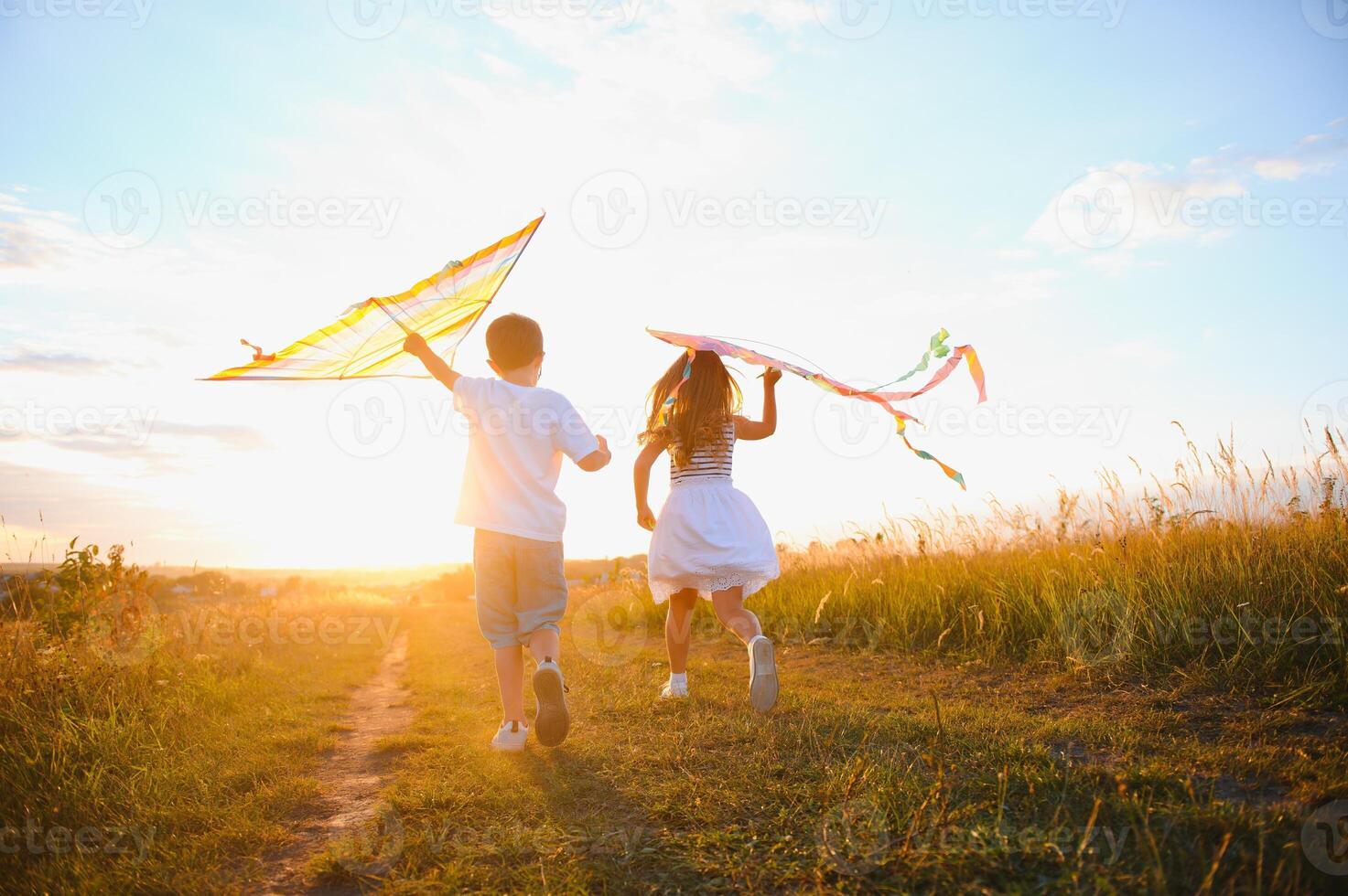 Happy children launch a kite in the field at sunset. Little boy and girl on summer vacation. photo