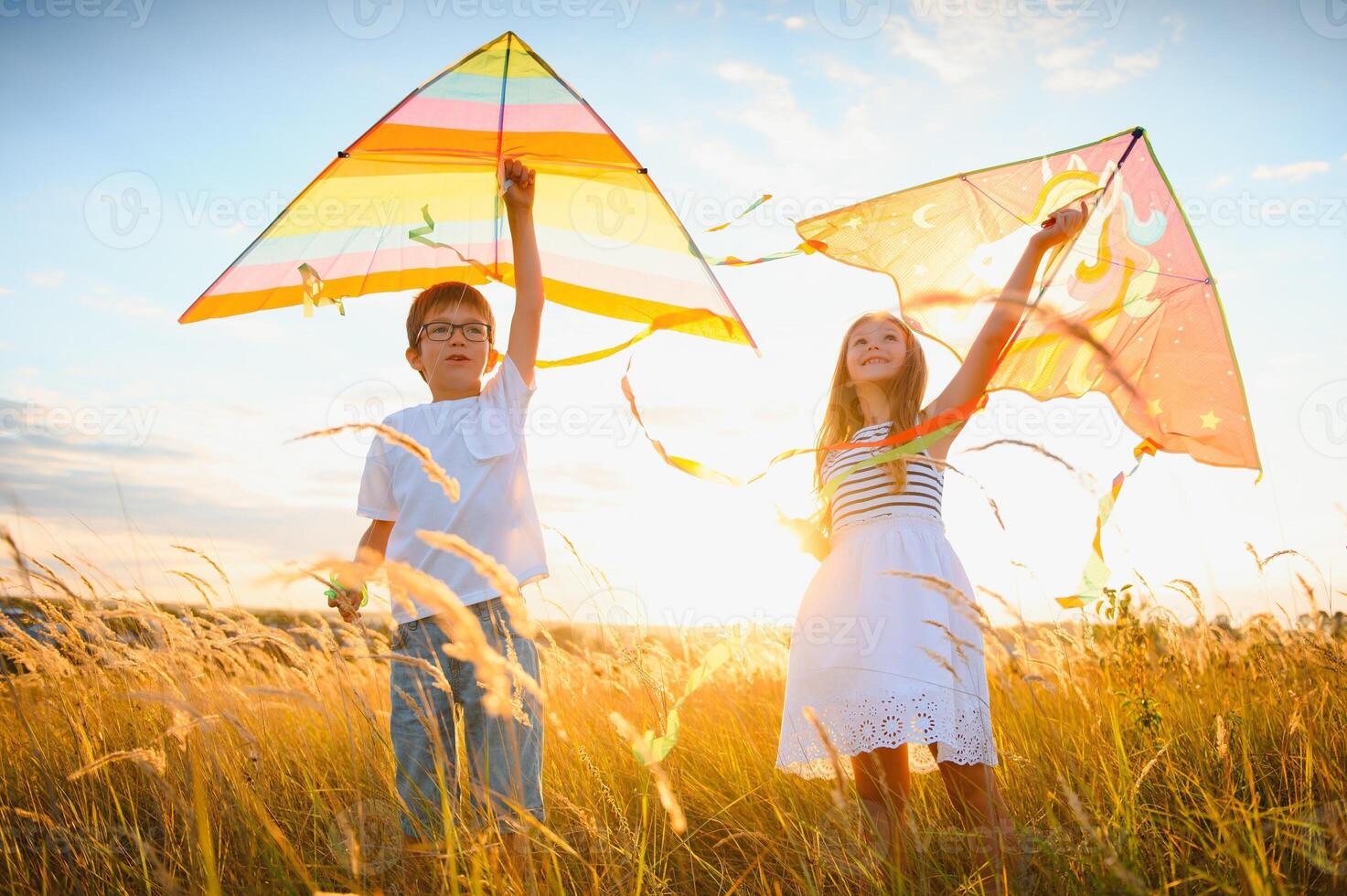 Children launch a kite in the field at sunset photo