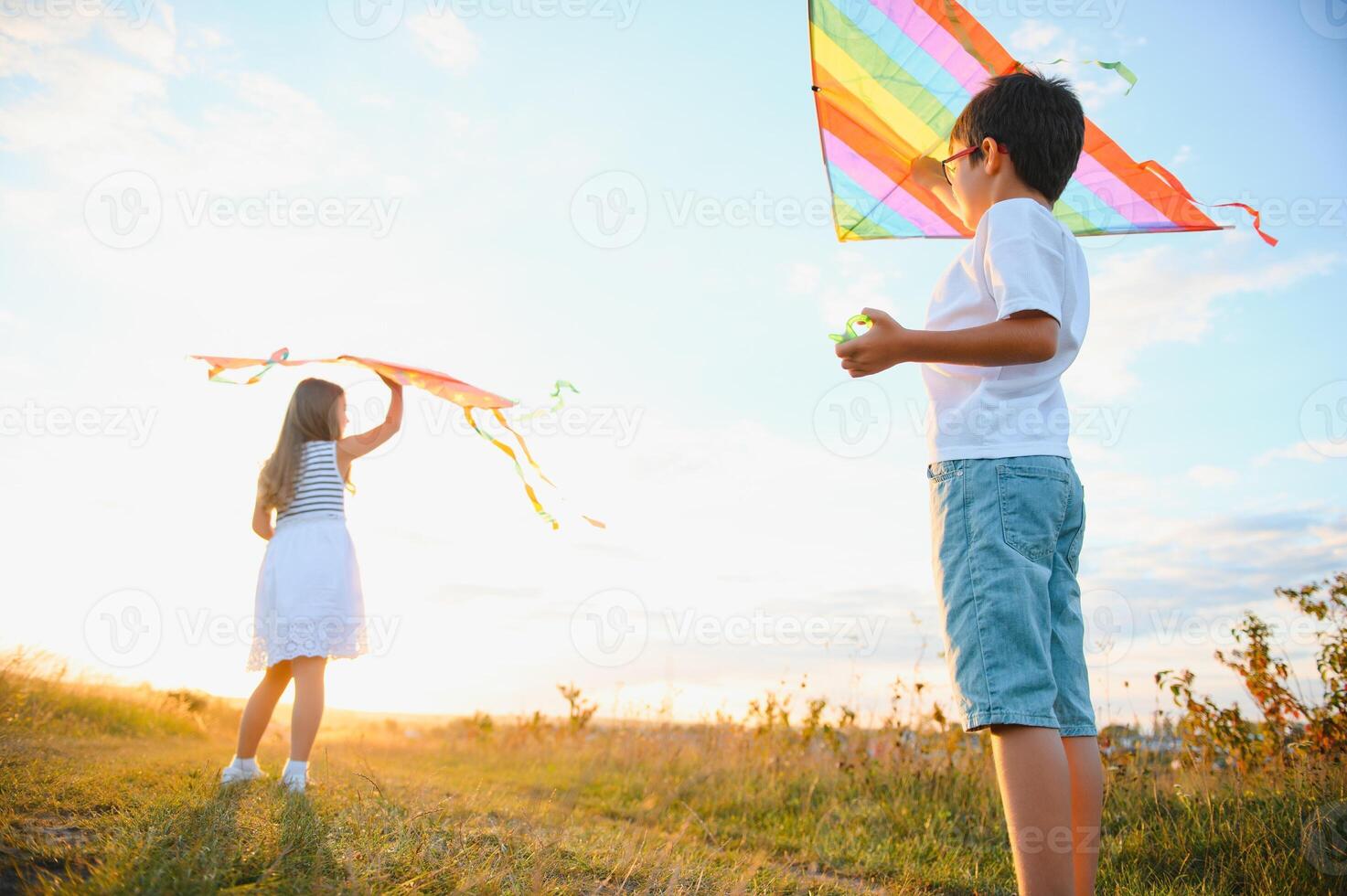 Children launch a kite in the field at sunset photo