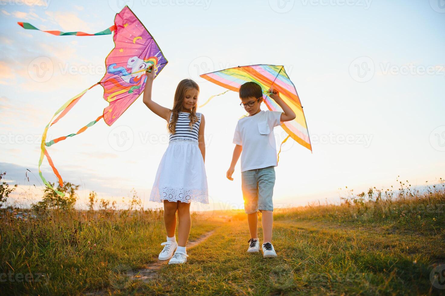 Happy children launch a kite in the field at sunset. Little boy and girl on summer vacation. photo