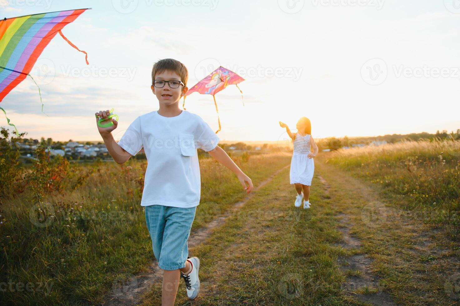 Children launch a kite in the field at sunset photo