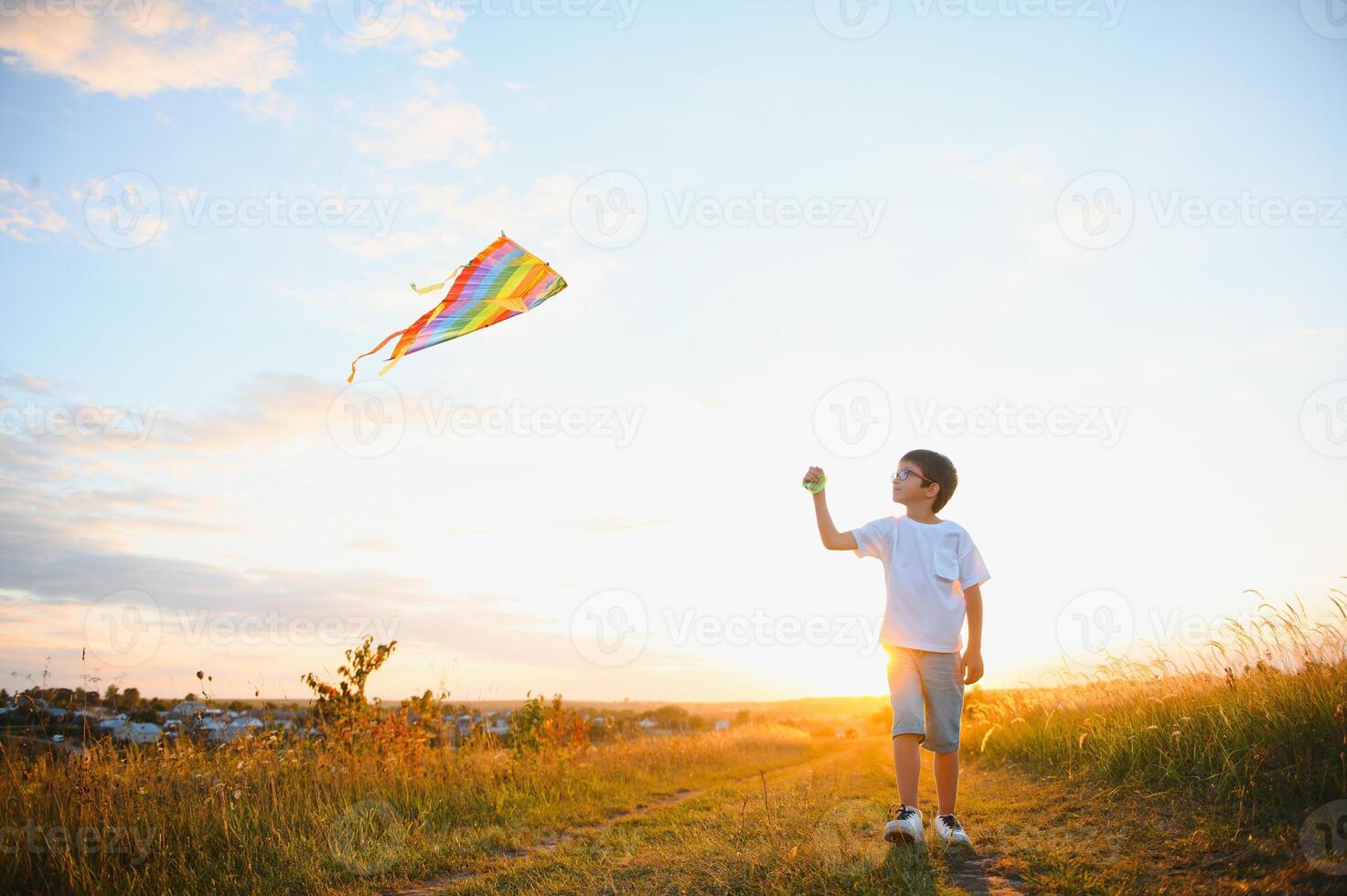 Little boy on summer vacation having fun and happy time flying kite on the field. photo