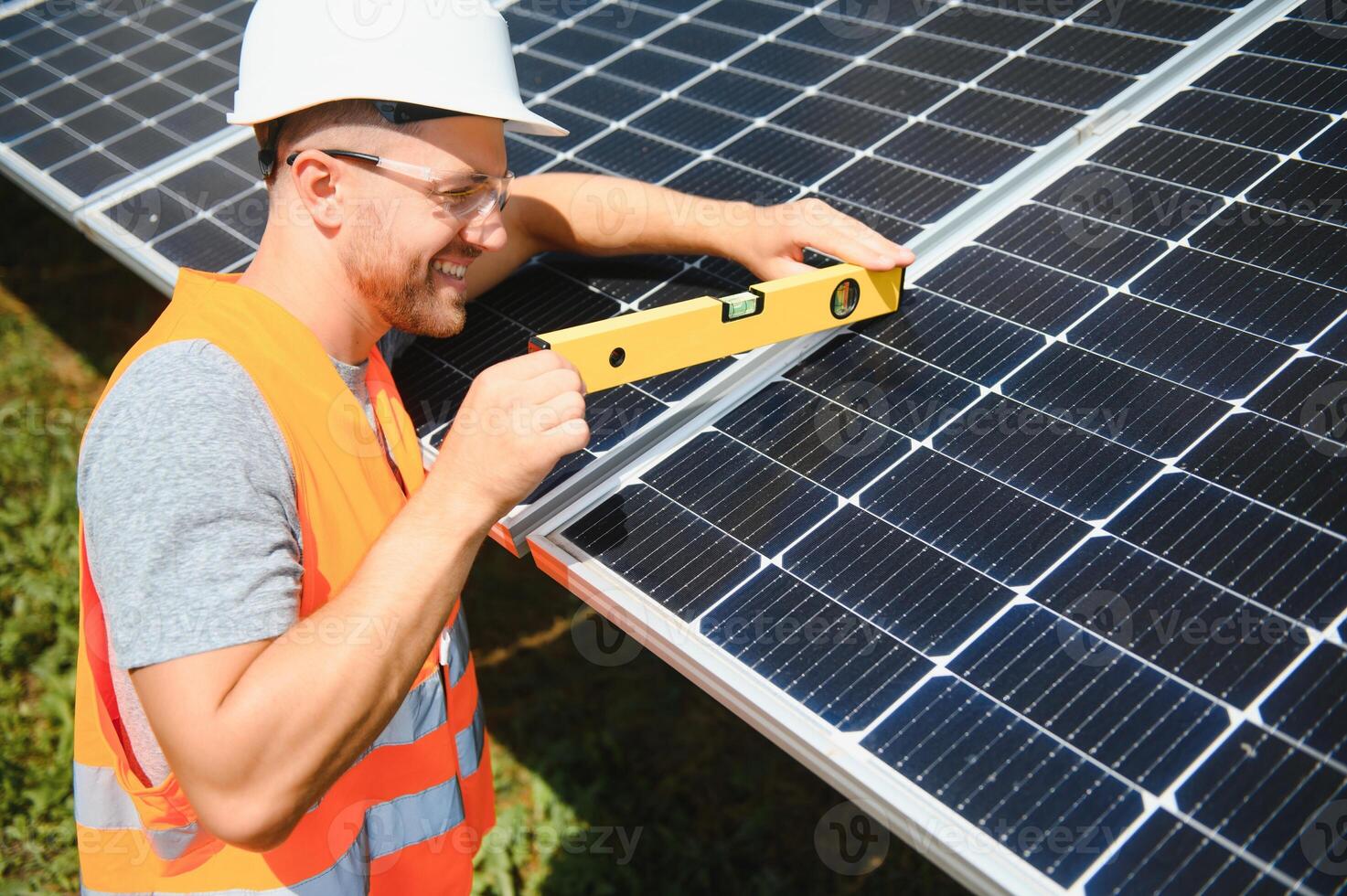 Male worker with solar batteries. Man in a protective helmet. Installing stand-alone solar panel system photo