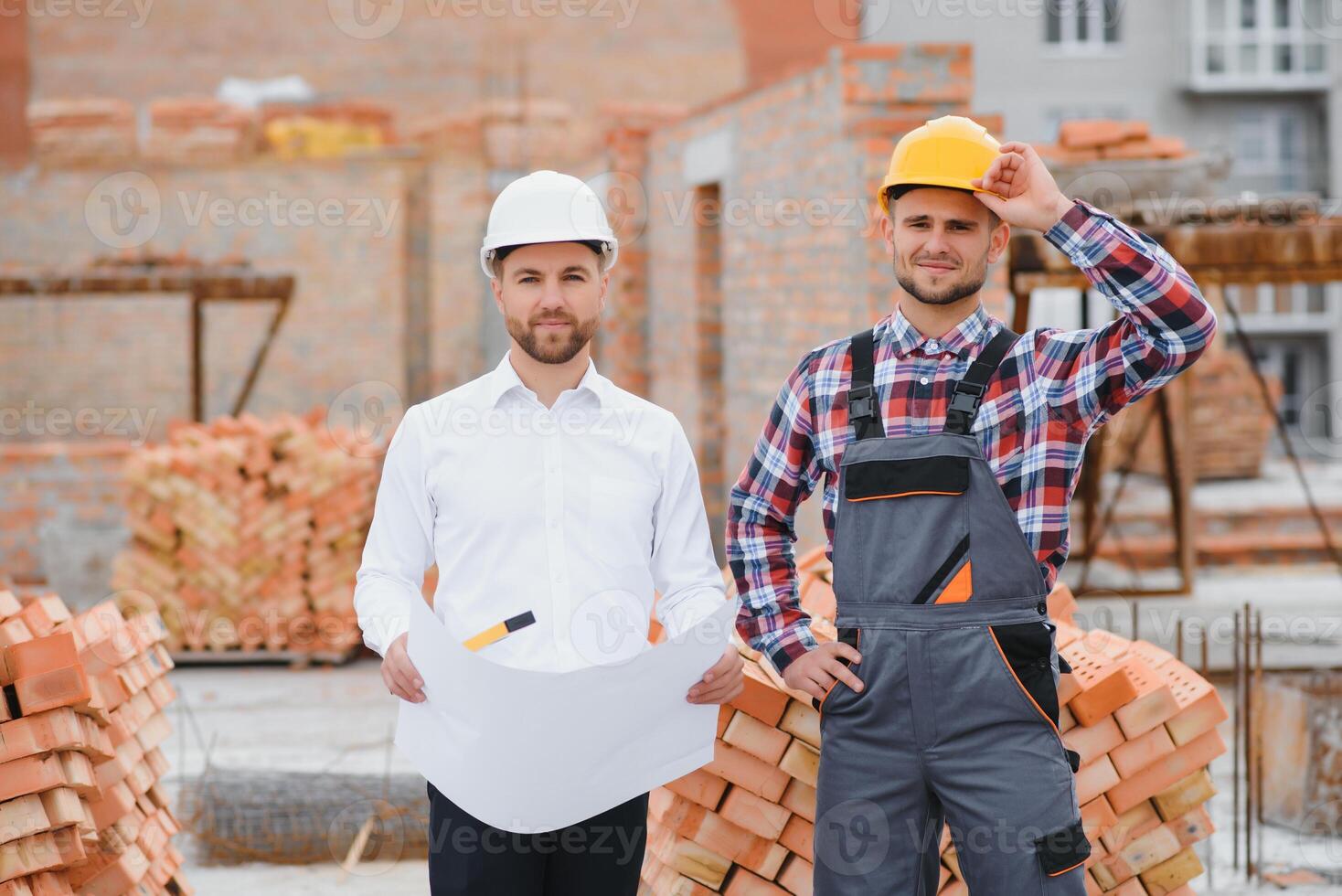 engineer architect with hard hat and safety vest working together in team on major construction site photo