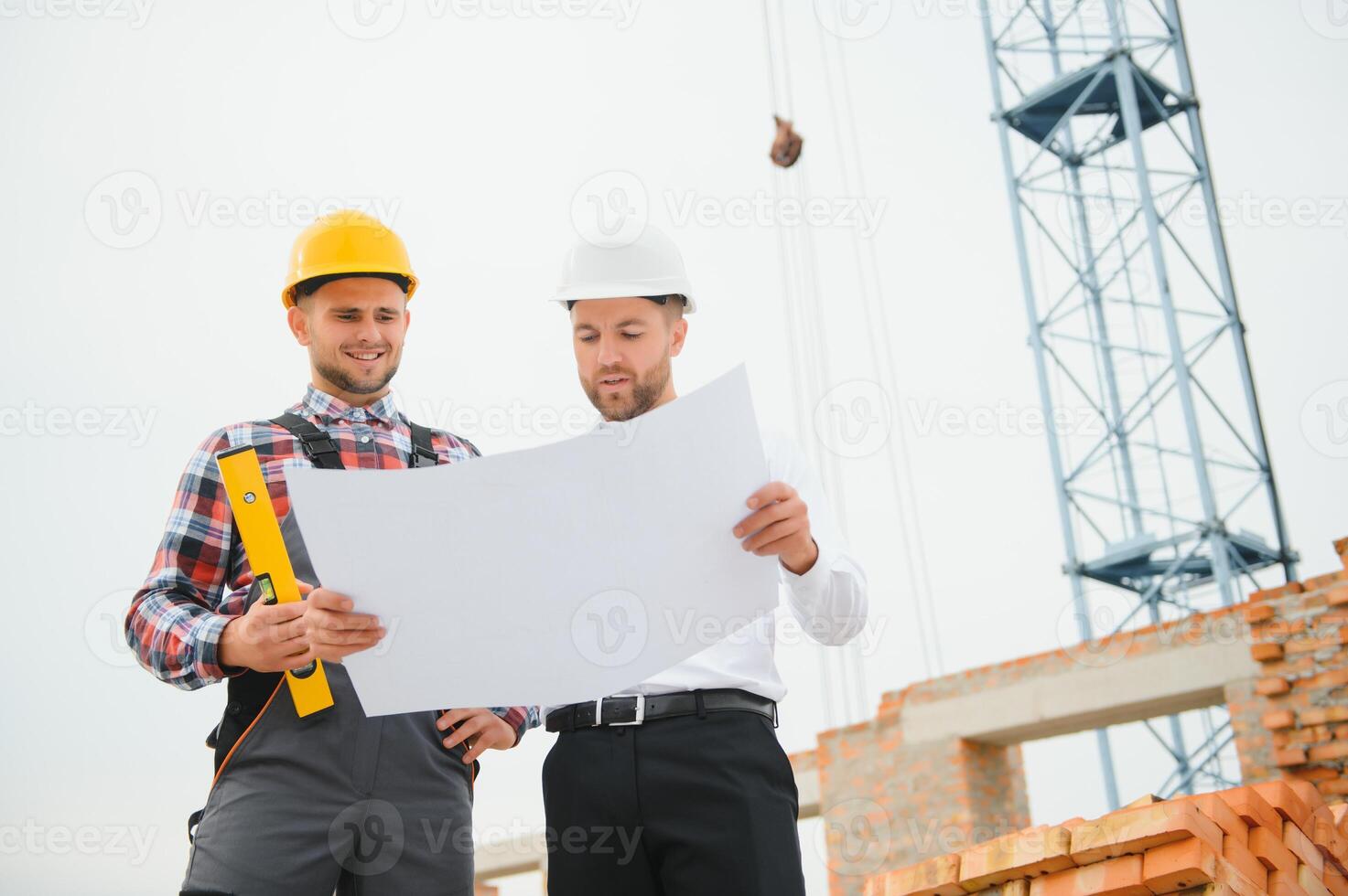 engineer and builder in hard hats discussing blueprint on construction site. photo