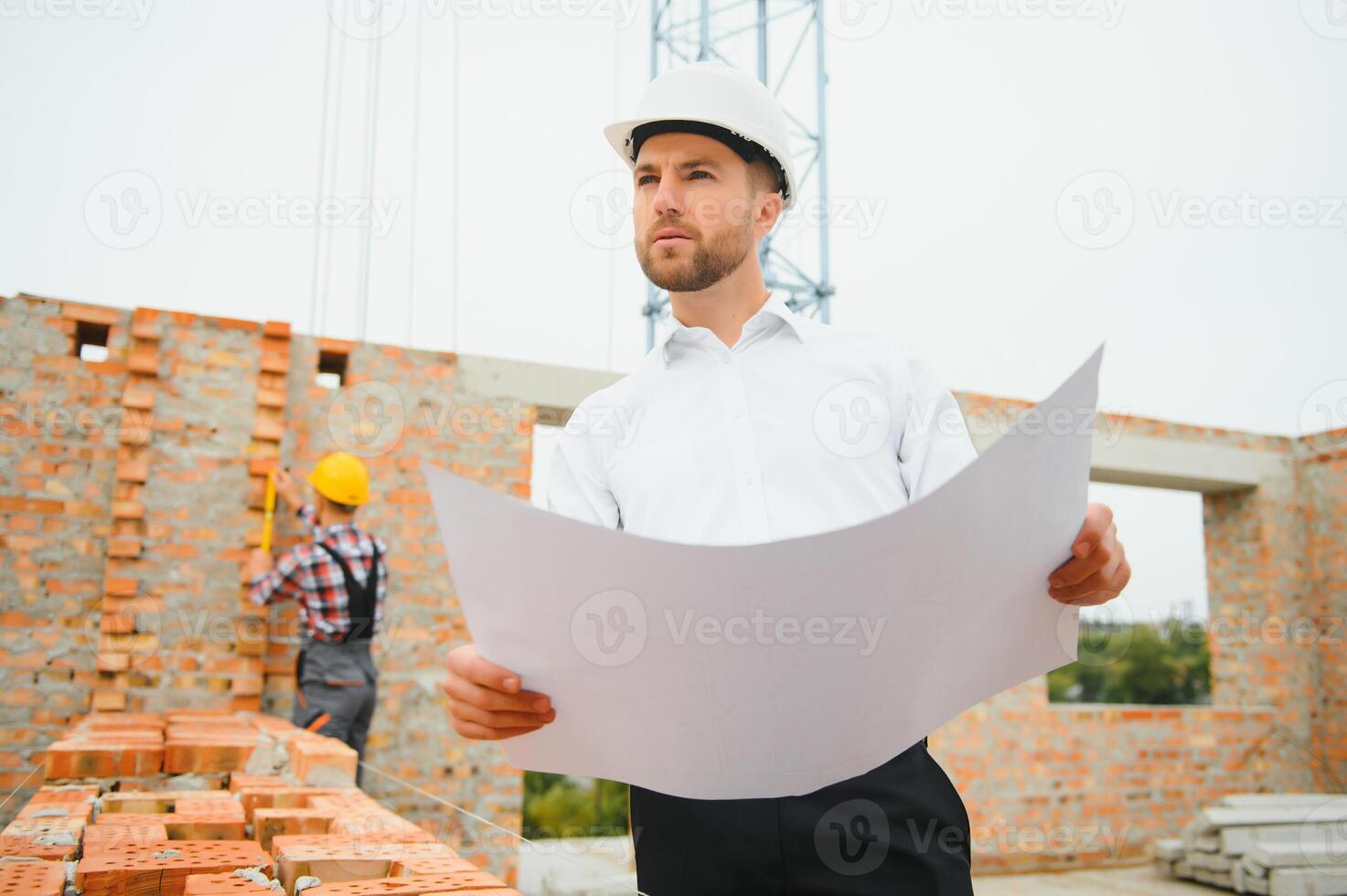 Construction engineer supervising progress of construction project stand on new concrete floor top roof and crane background. photo