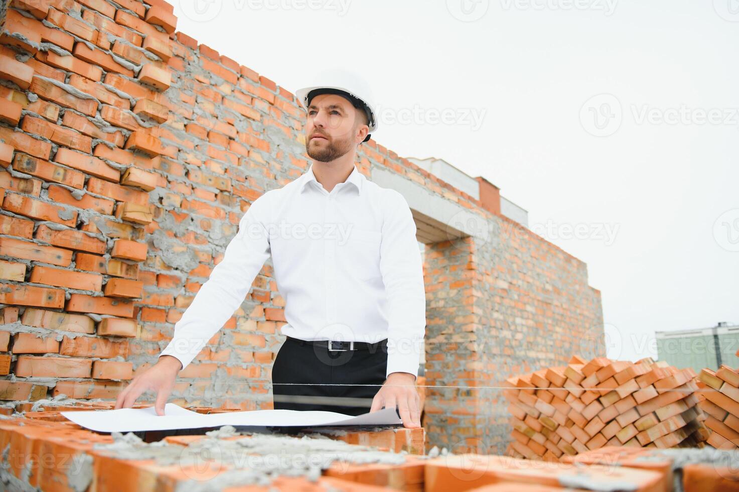 Architect at a construction site with blueprints photo