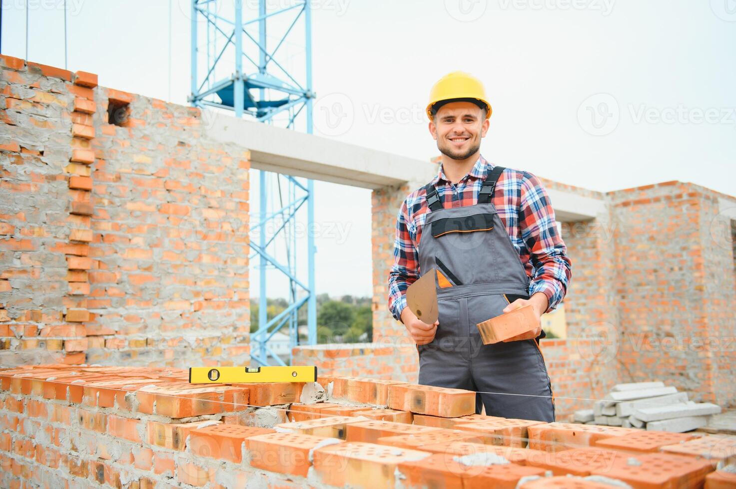 Construction worker man in work clothes and a construction helmet. Portrait of positive male builder in hardhat working at construction site. photo