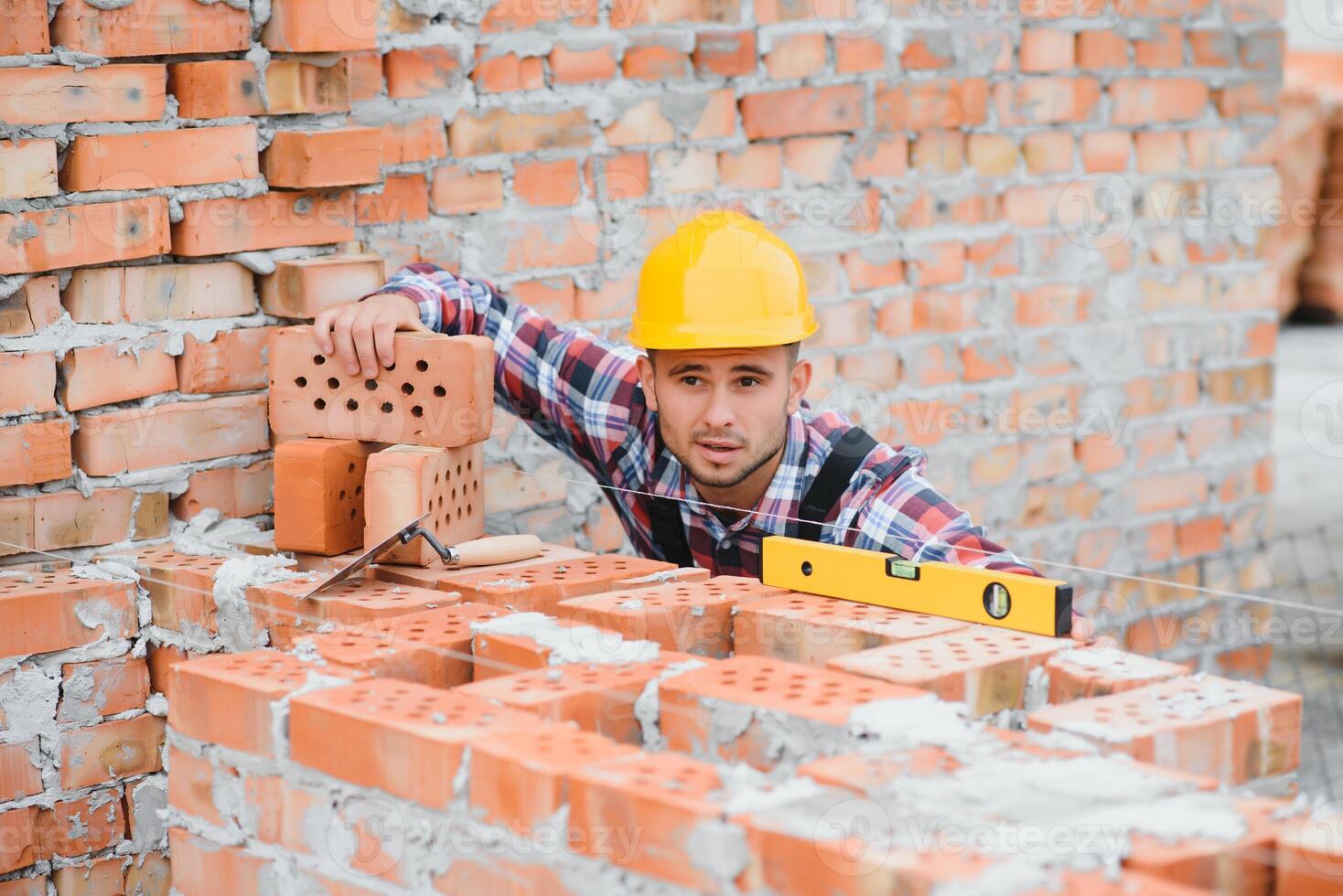 Construction worker man in work clothes and a construction helmet. Portrait of positive male builder in hardhat working at construction site. photo