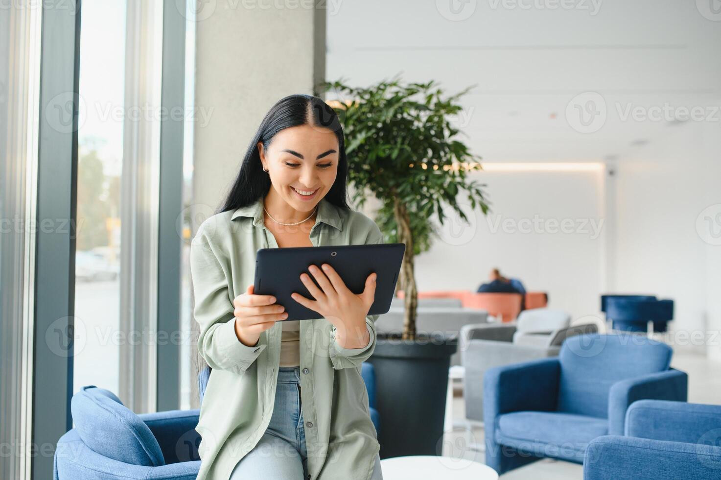 Young modern female freelancer in airport lounge or business center and works using digital tablet, creating new design project photo