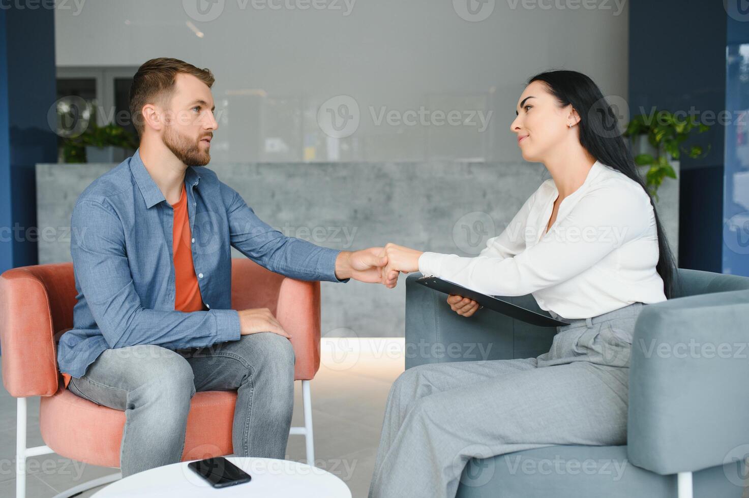 Psychologist talking with patient on therapy session. Depressed man speaking to a therapist while she is taking notes. photo