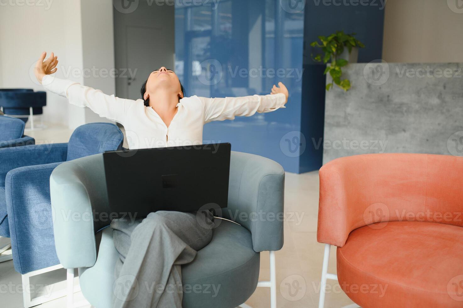 Young business woman sitting at sofa and working with laptop at the waiting hall of the business center photo
