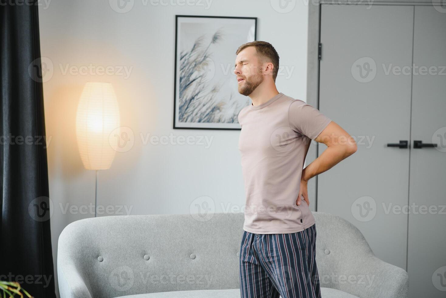 Back pain, kidney inflammation, man suffering from backache at home, health problems concept. photo