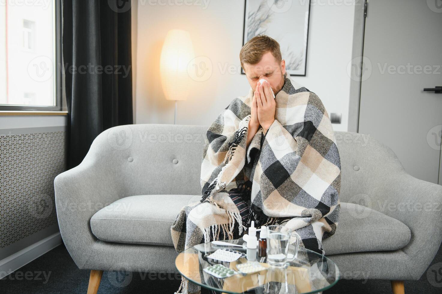 Sick man on sofa at home and blowing nose photo