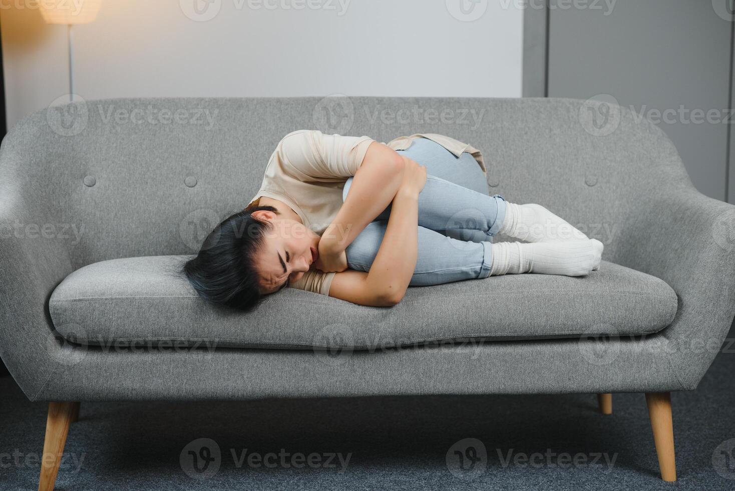 Young woman lying in the bed and suffering from gynecological problems, menstruation pain, stomach ache or abdominal pain. Menstruation period or PMS. photo