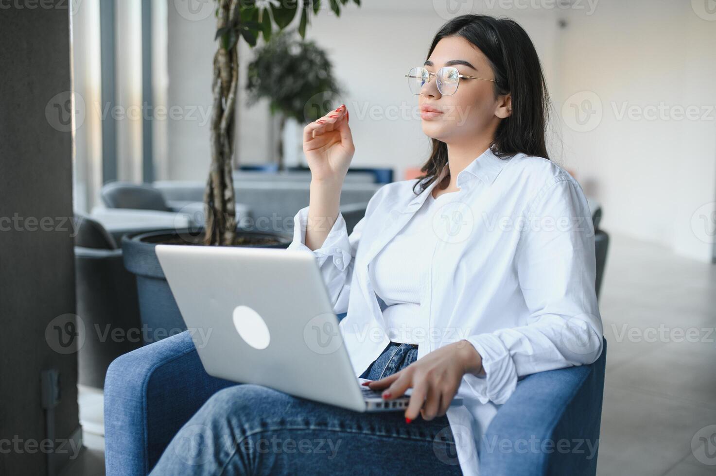 Beautiful Caucasian woman dreaming about something while sitting with portable net-book in modern cafe bar, young charming female freelancer thinking about new ideas during work on laptop computer photo
