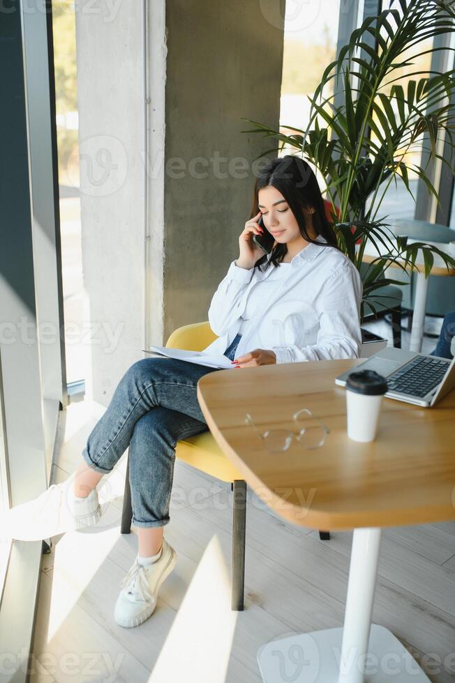 Beautiful Caucasian woman dreaming about something while sitting with portable net-book in modern cafe bar, young charming female freelancer thinking about new ideas during work on laptop computer photo