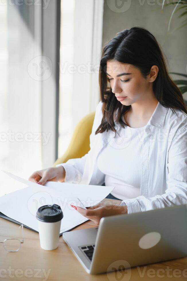 Beautiful Caucasian woman dreaming about something while sitting with portable net-book in modern cafe bar, young charming female freelancer thinking about new ideas during work on laptop computer photo